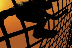 Man climbing a net during sunset. Spartan and gladiator race concept.